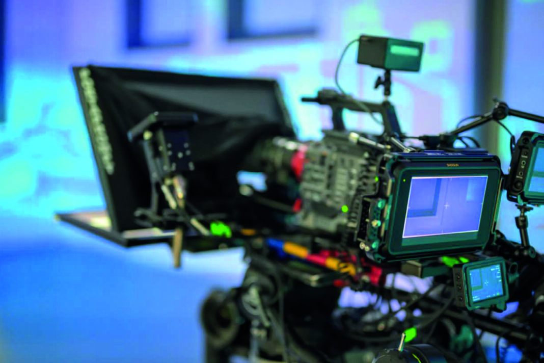 Professionelles Videokamera-Setup mit verschiedenen Monitoren, Kabeln und Zubehör. Die Hauptkamera und ihr digitales Display sind im Vordergrund gut sichtbar.
