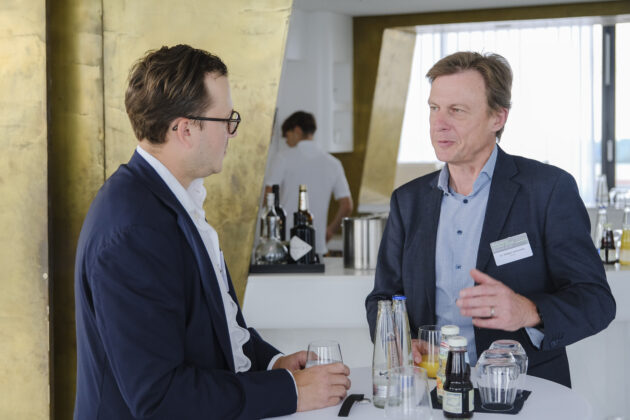 Menschen in Business-Casual-Kleidung unterhalten sich auf einem Firmen Event.