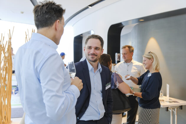 Menschen in Business-Casual-Kleidung unterhalten sich auf einem Firmen Event.