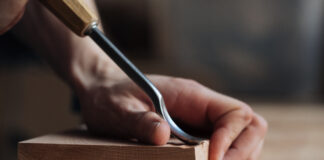 Symbolbild "Carve-out". (Wood carving, the master's hands work with a wooden surface, a professional does wood crafts.) Copyright: Александр Татаев - stock.adobe.com