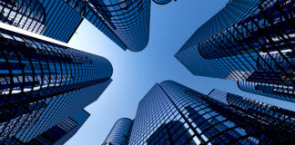 Low angle shot of modern glass city buildings with clear sky background.