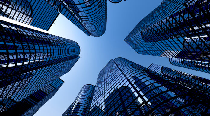 Low angle shot of modern glass city buildings with clear sky background.