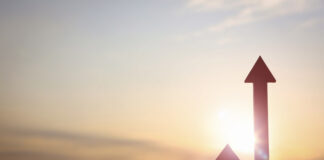 Symbolbild Aktienkurs. Arrow rising high and bright rising sun new year sunrise and stock finance economy industry growth investment target concept. Copyright: artpluskr - stock.adobe.com