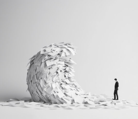 A wave of office paper symbolizes bureaucracy and swallows a businessman. Bureaucracy dismantle - danger concept. Copyright: Igor Link - stock.adobe.com