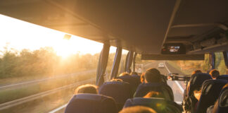 Symbolbild "Omnibus". Background. Travel by bus. Bus interior. Salon of the bus with people fill the sun with light in the sunset. People travel on a big tourist bus. The bus rides along the mornings. Copyright: bodnarphoto - stock.adobe.com