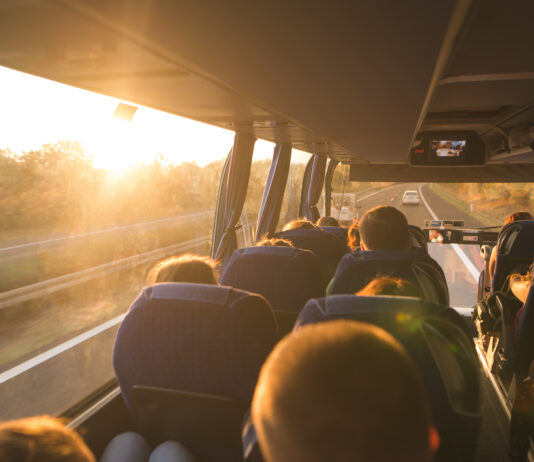 Symbolbild "Omnibus". Background. Travel by bus. Bus interior. Salon of the bus with people fill the sun with light in the sunset. People travel on a big tourist bus. The bus rides along the mornings. Copyright: bodnarphoto - stock.adobe.com
