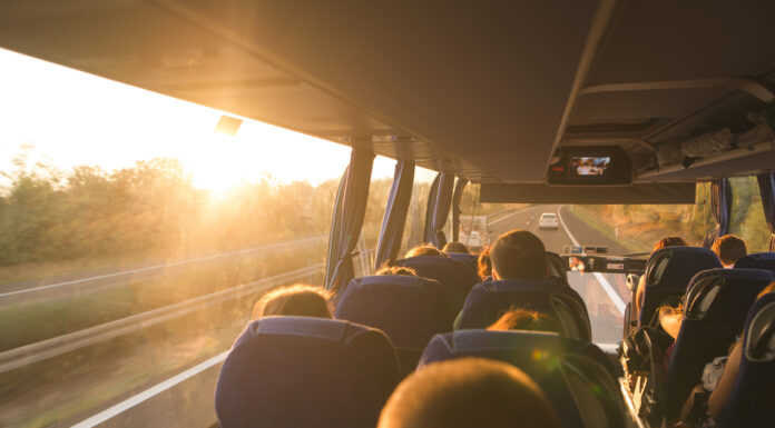 Symbolbild "Omnibus". Background. Travel by bus. Bus interior. Salon of the bus with people fill the sun with light in the sunset. People travel on a big tourist bus. The bus rides along the mornings. Copyright: bodnarphoto - stock.adobe.com
