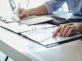Symbolbild "Internal Audit" (Examining the financial budget, a male auditor is pointing to a file to summarize the company's irregular financial budget). Copyright: Jirapong - stock.adobe.com