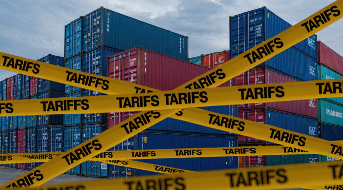 Symbolbild "Tariffs". American tariffs. Cargo Containers in Port with Yellow 'TARIFFS' Caution Tapes and American Flag Design, Overcast Sky Background. Copyright: Mohammad Xte - stock.adobe.com