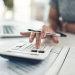 Finance planning, budget or savings manager calculating expenses, taxes or company profits with laptop, paperwork or calculator. Closeup hands of female financial leader checking office staff ... Copyright: N Felix/peopleimages.com - stock.adobe.com