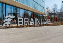 Brainlab lettering in front of the headquarters in Munich Riem with blue sky and sunshine. Copyright: Olaf Gedanitz - stock.adobe.com