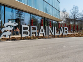 Brainlab lettering in front of the headquarters in Munich Riem with blue sky and sunshine. Copyright: Olaf Gedanitz - stock.adobe.com