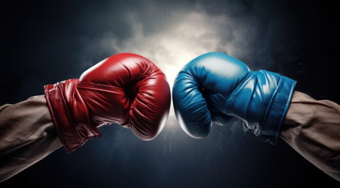 Symbolbild. Closeup two man hands in red and blue boxing gloves hitting each other on isolated dark misty background. Copyright: GulArt - stock.adobe.com