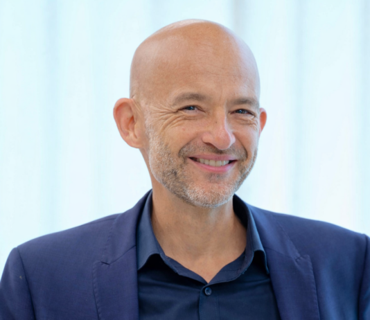 „Wir setzen nicht auf ein einzelnes Pferd, sondern auf das ganze Rennen.“ Prof. Dr. Andreas Zaby, Innovationsmanager, SPRIND GmbH. Quelle/Copyright Foto: Wikipedia / Heinrich-Böll-Stiftung - Grüner Wirtschaftstag 2025. Bildhintergrund nachbearbeitet mit KI