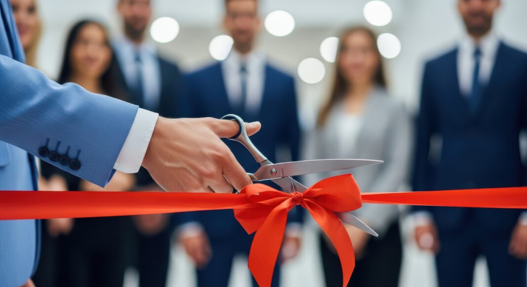 Close-up of hands cutting a red ribbon with scissors during a grand opening ceremony, symbolizing business launch and inauguration Foto: © Zra - AdobeStock