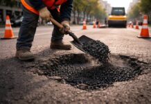 Gegen die Löcher auf der Straße Symbolbild: Worker fixing pothole with asphalt mix. Close up road damage repair process. Street maintenance and road fix work. Urban road safety and service concept. Construction worker repairing pavement. Copyright: Alina - stock.adobe.com