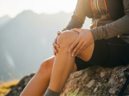 Case Study: BIONCaRT – Stammzellen für die Regeneration geschädigter Gelenke Symbolbild. Closeup of a hiker holding their knee in pain while sitting on a rock during a mountain hike at sunset. Copyright: ViskBx - stock.adobe.com
