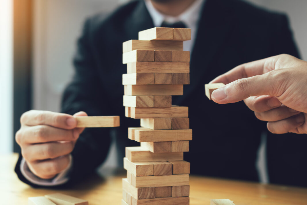 Strategic thinking and risk by business people pulls wooden blocks from the group. Symbolbild "Jenga". Strategic thinking and risk by business people pulls wooden blocks from the group. Cppyright: wutzkoh - stock.adobe.com